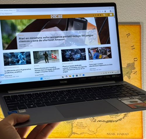 Ordenador portátil TECNO MEGABOOK T15RA sostenido con una mano mostrando una página web de noticias en pantalla.