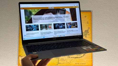 Ordenador portátil TECNO MEGABOOK T15RA sostenido con una mano mostrando una página web de noticias en pantalla.