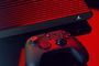 Consola Atari VCS con carcasa de rejilla y mando inalámbrico sobre una superficie oscura bajo iluminación roja.