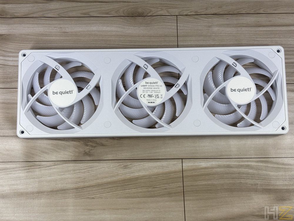 Tres ventiladores blancos be quiet! Light Wings Pro montados en línea sobre una superficie de madera.