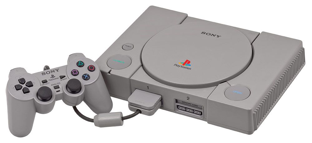 Consola PlayStation original de color gris con un mando DualShock conectado sobre fondo blanco.