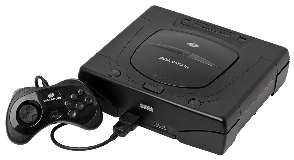 Consola SEGA Saturn en color negro con su mando de control conectado en el frontal sobre fondo blanco.