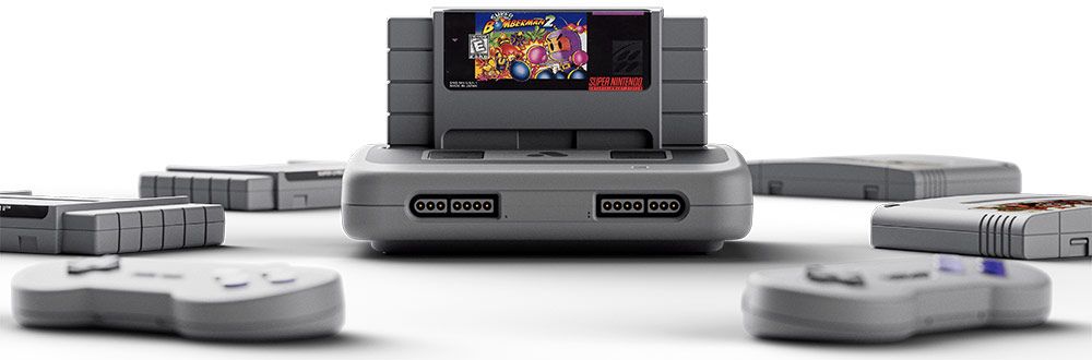 Consola Super Nt+ de color gris con un cartucho insertado, mandos inalámbricos y varios juegos alrededor sobre fondo blanco.