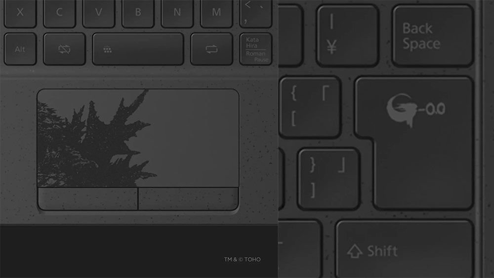 Detalle del panel táctil y la tecla Enter de un portátil Fujitsu con grabados decorativos de la película Godzilla Minus One.