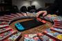 Consola Nintendo Switch rodeada de cajas de juegos en formato físico sobre una mesa de madera.