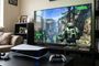 Consola PS5 con mandos DualSense frente a un televisor que muestra una partida del videojuego Halo.