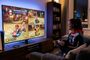 Una persona juega a Mario Kart 8 Deluxe en pantalla dividida sentada frente a un televisor con una consola PS5 al lado.