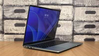 Ordenador portátil abierto sobre una mesa de madera mostrando la pantalla de bloqueo de Windows 11.