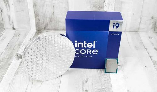 Procesador Intel Core i9-14900 junto a su embalaje azul y una oblea de silicio sobre una superficie de madera clara.