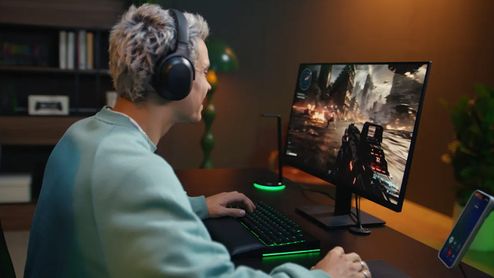 Usuario con auriculares Razer Barracuda v2 frente a un monitor gaming con un videojuego de acción.