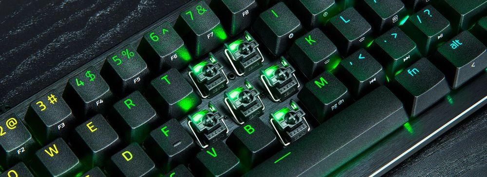 Primer plano de los interruptores mecánicos con iluminación verde bajo las teclas de un teclado Razer Huntsman V3 Pro.