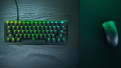 Teclado Razer Huntsman V3 Pro con iluminación RGB verde y ratón inalámbrico sobre un escritorio de madera oscura.