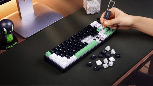 Proceso de extracción de teclas en un teclado Razer Reclusa Mini mediante una herramienta específica sobre una alfombrilla negra.
