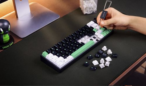 Proceso de extracción de teclas en un teclado Razer Reclusa Mini mediante una herramienta específica sobre una alfombrilla negra.