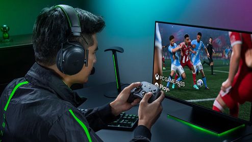 Usuario jugando a un videojuego de fútbol en PC con el mando Razer Wolverine V4 Pro y auriculares de diadema.