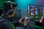 Usuario jugando a un videojuego de fútbol en PC con el mando Razer Wolverine V4 Pro y auriculares de diadema.