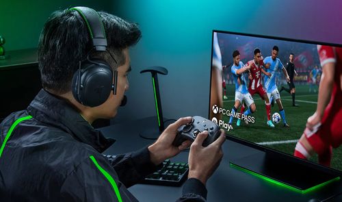 Usuario jugando a un videojuego de fútbol en PC con el mando Razer Wolverine V4 Pro y auriculares de diadema.