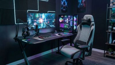 Silla gaming Newskill Neith Zephyr situada frente a un escritorio con PC, monitor ultrapanorámico e iluminación RGB.